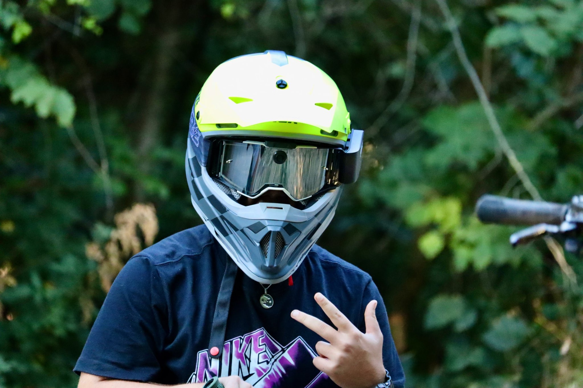Motocross rider wearing a yellow helmet and PURE MX1 goggles with integrated action camera, in the forest
